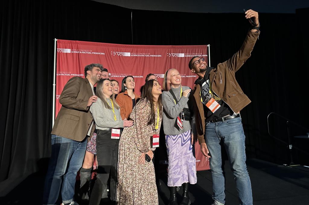 A group of people take a selfie in front of a red background